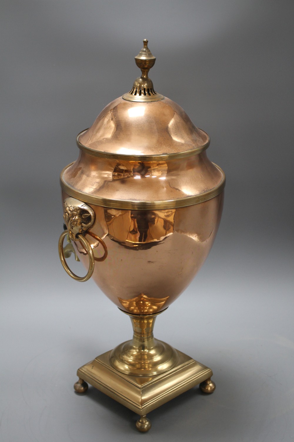 A Regency brass mounted copper tea urn, with rams mask ring handles, height 51cm